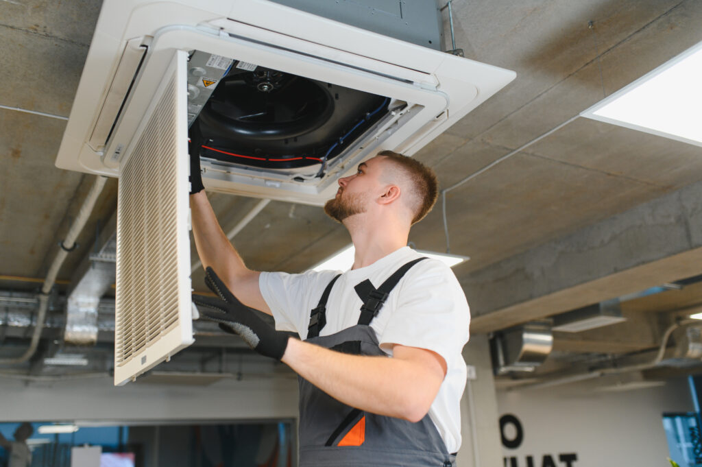 Hvac technician servicing ceiling air conditioning unit filter
